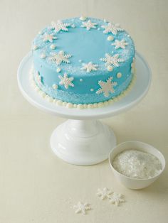 a blue frosted cake sitting on top of a white plate next to a bowl