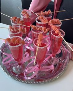 there are many glasses with drinks in them on the tray and one is filled with candies