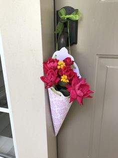 a bouquet of flowers in a paper cone hanging on the door way to an apartment