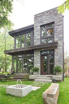 a modern house with large windows and stone steps leading up to the front porch area