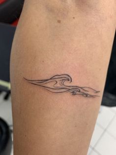 a woman's leg with a wave tattoo on it