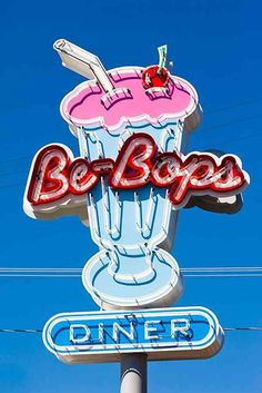 a neon sign for a diner with a large ice cream sundae on it's side