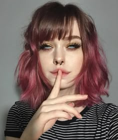 a woman with pink hair is posing for the camera and has her finger on her lips