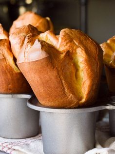 several muffins sitting in metal pans on a table with white towels around them