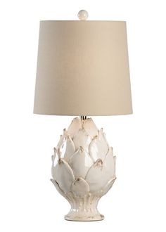 a white lamp with a beige shade on it's base and a light bulb in the shape of a flower