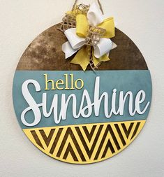 a sign that says hello sunshine hanging on the side of a wall with a bow