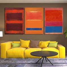 a living room with yellow couches and paintings on the wall above it's coffee table