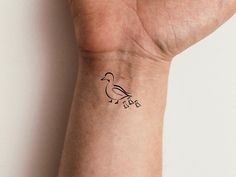 a small tattoo on the wrist of a woman's arm, with a bird