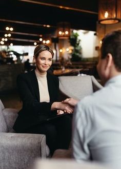 a woman sitting in a chair talking to a man who is holding his hand out