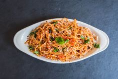 a white plate topped with pasta covered in parmesan cheese and basil leaf sprinkles