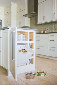 a dog is eating food out of a dishwasher in the kitchen with its door open