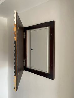 an open door on the side of a wall in a room with white walls and wood trim