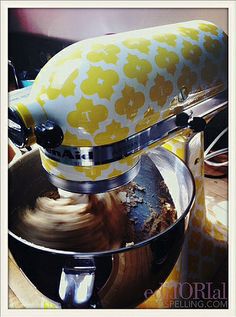 a yellow and white mixer sitting on top of a table