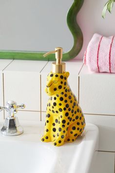 a yellow and black spotted animal soap dispenser sitting on a bathroom sink