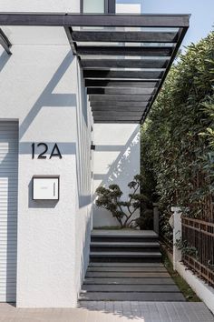 an entrance to a house with steps leading up to the front door and number on the wall