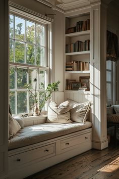 a window seat with pillows on it in front of a book shelf filled with books