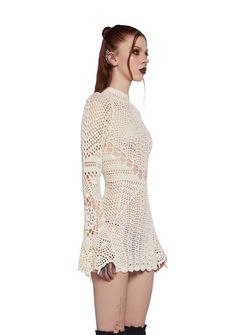 a woman in short shorts and boots is wearing a white crochet top with long sleeves