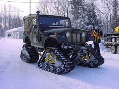 two men standing next to an army jeep with snowmobiles on it's tires