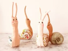 three stuffed animals sitting next to each other on a marble counter top with shells in the shape of bunnies