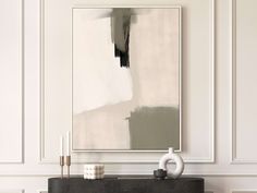 an abstract painting hangs on the wall above a console