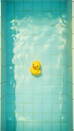 a yellow rubber duck floating in a blue swimming pool with white tiles on the walls