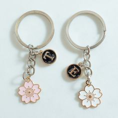 two keychains with letters and flowers on them, one has a flower charm