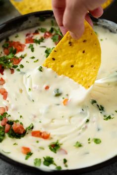 a hand dipping a tortilla chip into a bowl of quesadilla dip