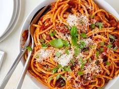 a bowl of spaghetti with sauce and parmesan cheese on the side next to a fork