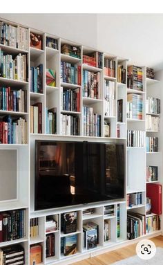 a living room filled with lots of books and a flat screen tv mounted on a wall