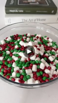 a bowl filled with candy and marshmallows on top of a table next to a book