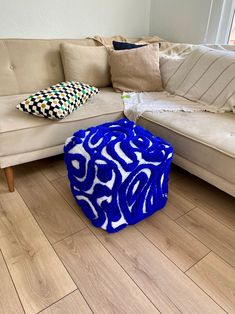 a blue and white ottoman sitting on top of a wooden floor next to a couch