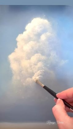 a person holding a brush in front of a cloud