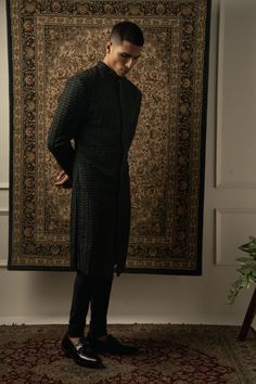 This stunning black sherwani epitomizes geometric sharpness, boasting intricate tonal embroidery on a silk base. Each stitch is meticulously handcrafted to perfection, creating an illusion of fabric that mesmerizes the eye. With its impeccable craftsmanship and attention to detail, this sherwani stands as a true testament to sophistication and style, making it the ideal choice for any formal occasion or cultural celebration.From Jigar & Nikita's Summer Romance collection. DELIVERY TIMEPlease all Ceremonial Black Kurta With Naqshi Detailing, Ceremonial Black Kurta With Naqshi, Designer Black Kurta With Naqshi, Black Sherwani With Chikankari Embroidery, Black Chikankari Embroidered Sherwani, Black Chikankari Embroidery Sherwani, Ceremonial Black Naqshi Traditional Wear, Designer Black Nehru Jacket With Traditional Drape, Black Fitted Bandhgala With Naqshi