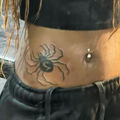 a woman's stomach with a spider tattoo on her belly and the bottom part of her lower body