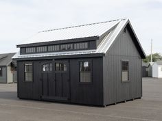 a small black building sitting in the middle of a parking lot