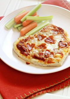 a white plate topped with pizza next to carrots and celery