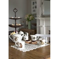 a table topped with cups and saucers filled with pastries on top of a wooden table