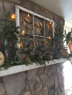 a fireplace mantle decorated with christmas decorations and greenery in front of an old window