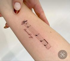 a woman's arm with a musical note tattoo on it