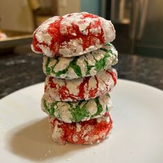 a stack of colorfully decorated cookies sitting on top of a white plate next to a counter