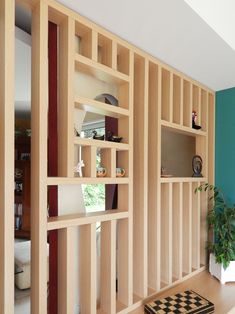 a living room filled with furniture next to a green wall and wooden shelves on the wall