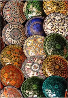 many colorful plates are stacked on top of each other in this photo, one has an intricate design