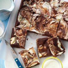 some brownies are cut into squares and sitting on a cutting board next to a bowl of yogurt