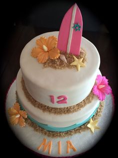 a three tiered cake decorated with flowers and a surfboard on the top layer