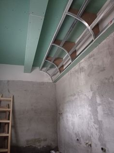 an unfinished room with green paint and white plaster on the ceiling is being worked on