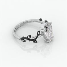 a diamond engagement ring with an oval cut center stone and black accents on the band