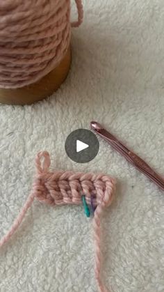 the crochet hook is next to a ball of yarn and a knitting needle