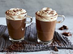 two glasses of hot chocolate drink with whipped cream on top