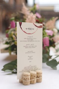 wine corks sitting on top of a table next to a menu and some flowers