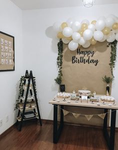 a birthday party setup with balloons and desserts on the table in front of a happy birthday sign